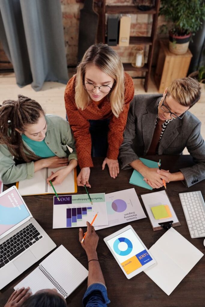 The Art of Drawing Readers In: Your attractive post title goes here Top view of a diverse group discussing business reports and charts around a desk.